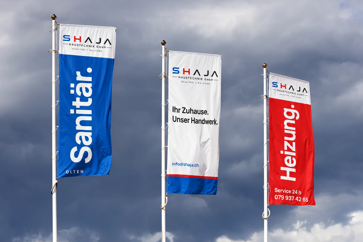 Drei SHAJA-Fahnen mit Sanitär in Blau, Ihr Zuhause. Unser Handwerk. und Heizung in Rot